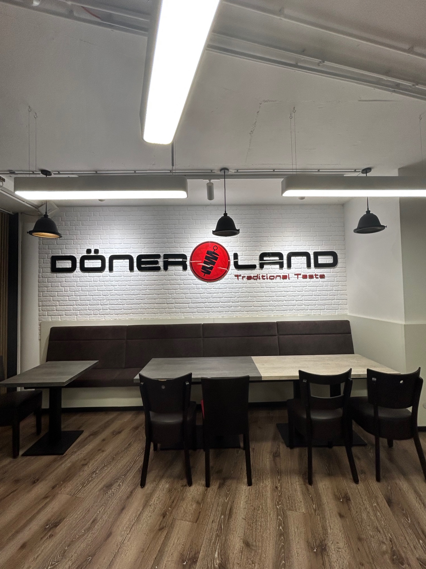 DönerLand Logo an der weißen Backsteinwand im Innenraum