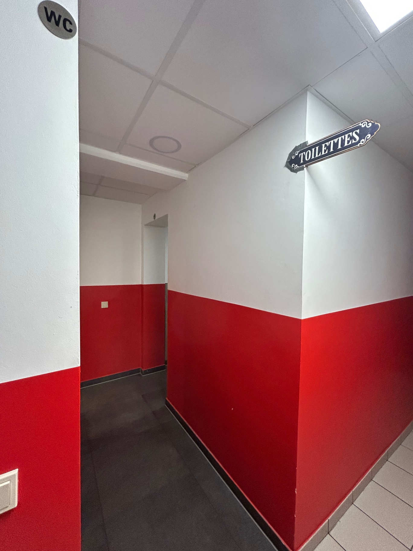 Wegbeschreibung zu den Toiletten: blaues 'Toilettes'-Schild im unteren Flur